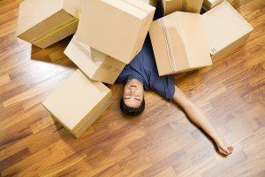 High angle view of young man sleeping underneath moving boxes